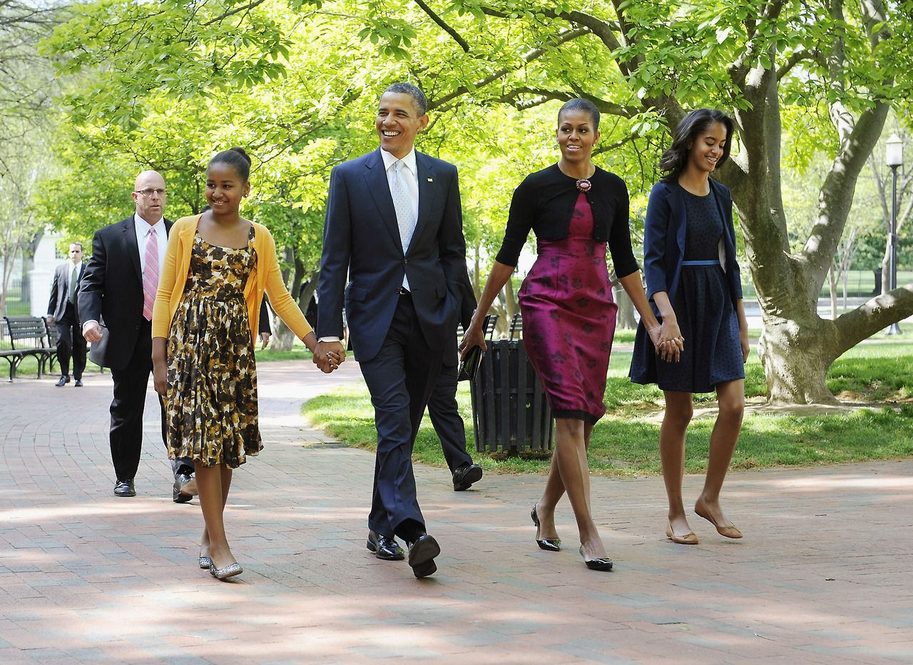 Obama and his wife Michelle smile at reporters as they walk from the White House to an Easter Church service with their daughters in Washington